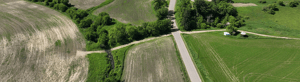 Aerial view of rural farmland with fields, roads, and agricultural buildings.