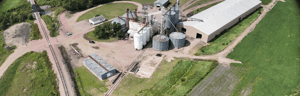 Grain storage and processing facility surrounded by farmland, with rail lines connecting to the site.