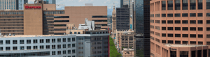 Skyline of downtown Denver with a mix of modern and historic buildings under a partly cloudy sky.