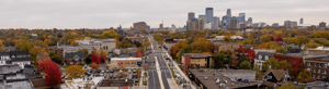 Aerial view of a reconstructed city avenue leading toward a downtown skyline in fall.