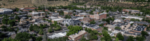 Banner image of an aerial view of downtown Durango, Colorado, surrounded by green hills and mountains under a clear blue sky.