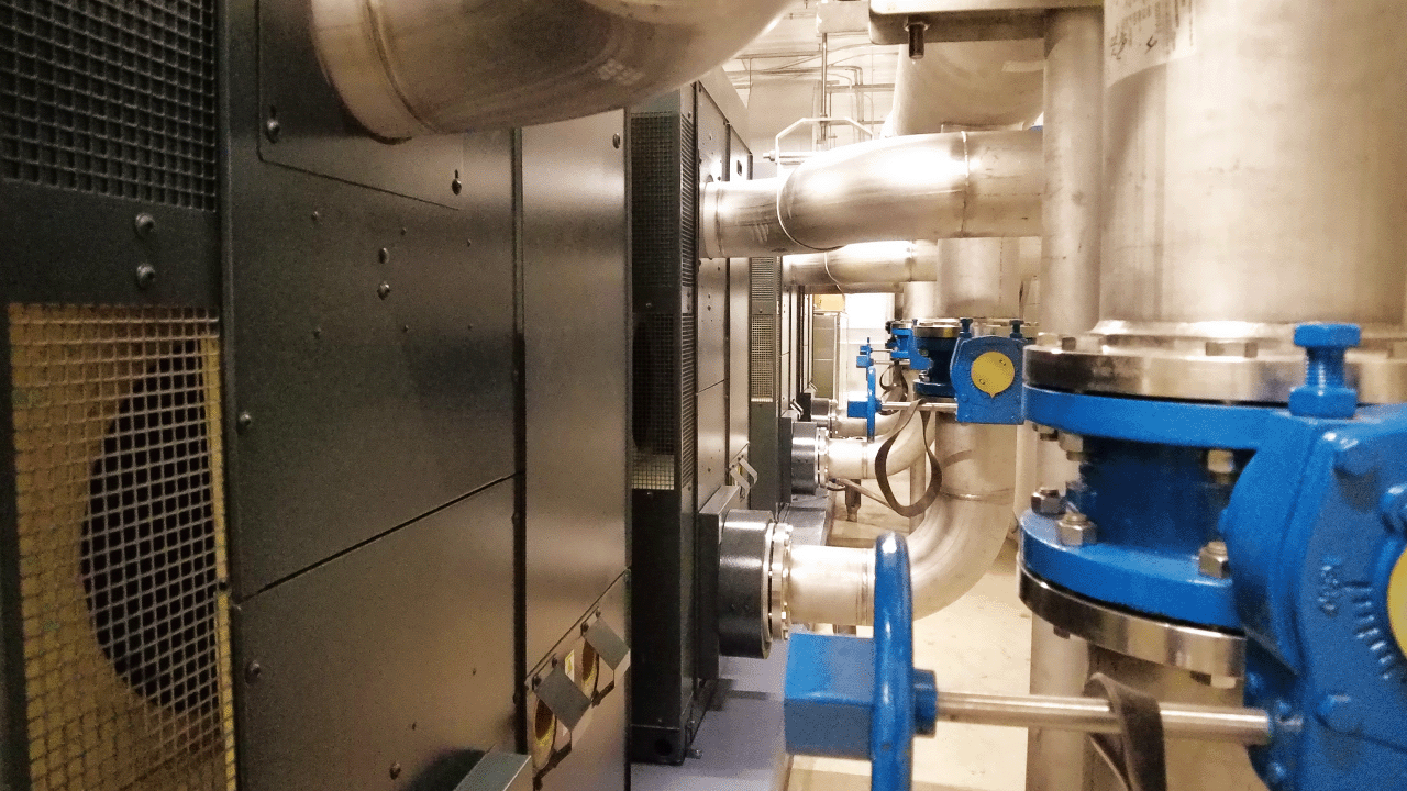 Section of Medford's wastewater treatment plant with silver pipes, blue valves, and industrial machinery in the background.