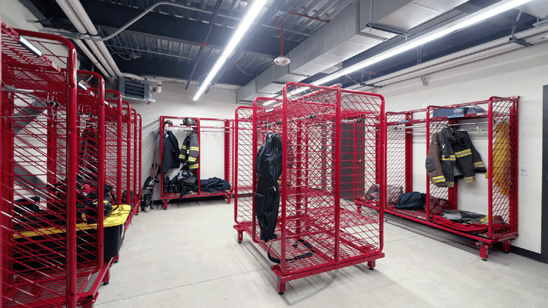 Image of the fire station's equipment storage room with coats hanging from red racks.