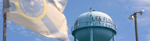 Close-up of a blue water tower labeled 'Lee Florida' with a flag in the foreground and a clear sky in the background.