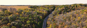A winding road cutting through a forest with autumn foliage.